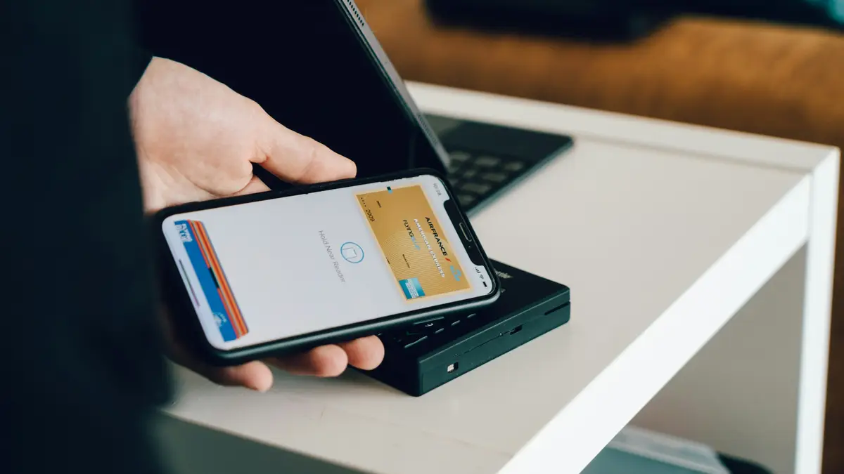 A phone showing a card in its wallet, held over a reader