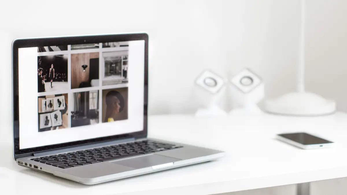 A laptop on a white desk showing a website