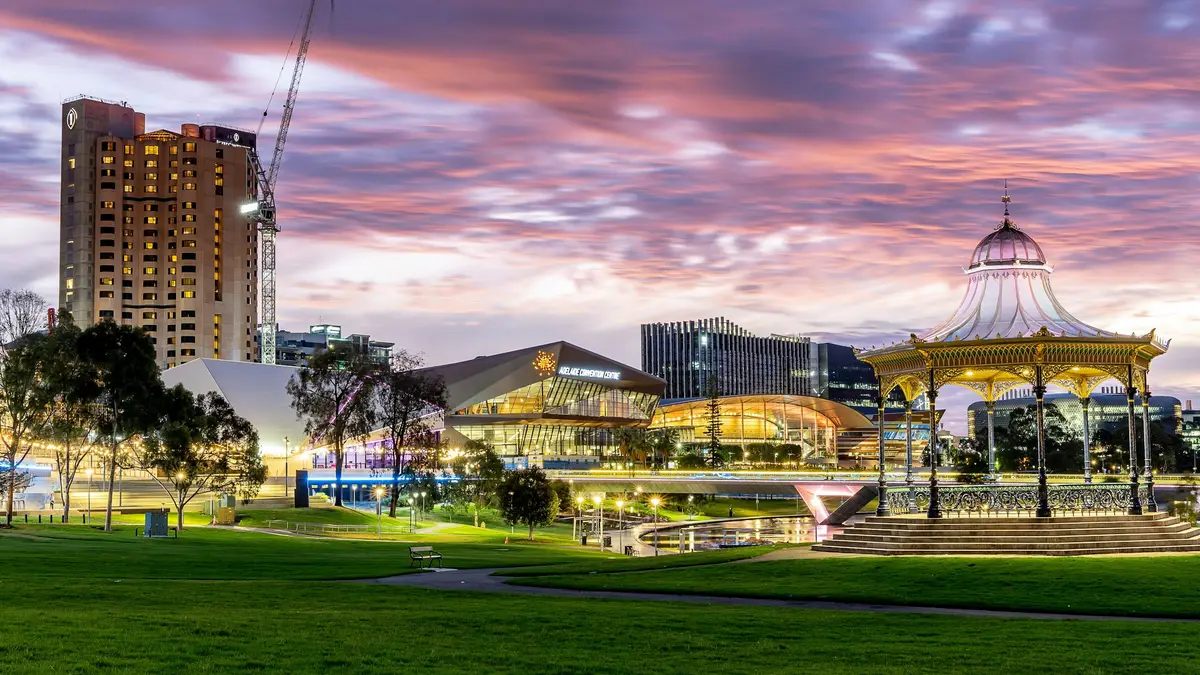 Adelaide's riverbank parkland and city at dusk, with a rotunda in the foreground